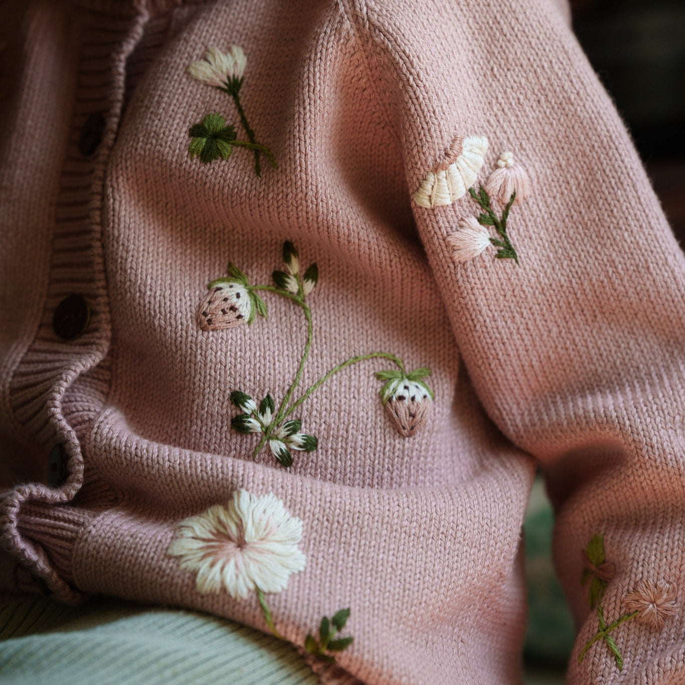 Child wearing a pink sweater with floral embroidery