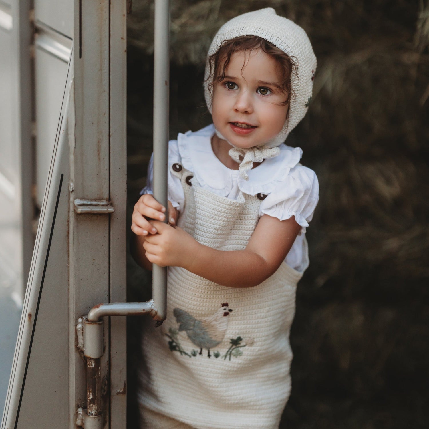 Baby wearing the Little Farm Romper - Malt, surrounded by a natural setting.