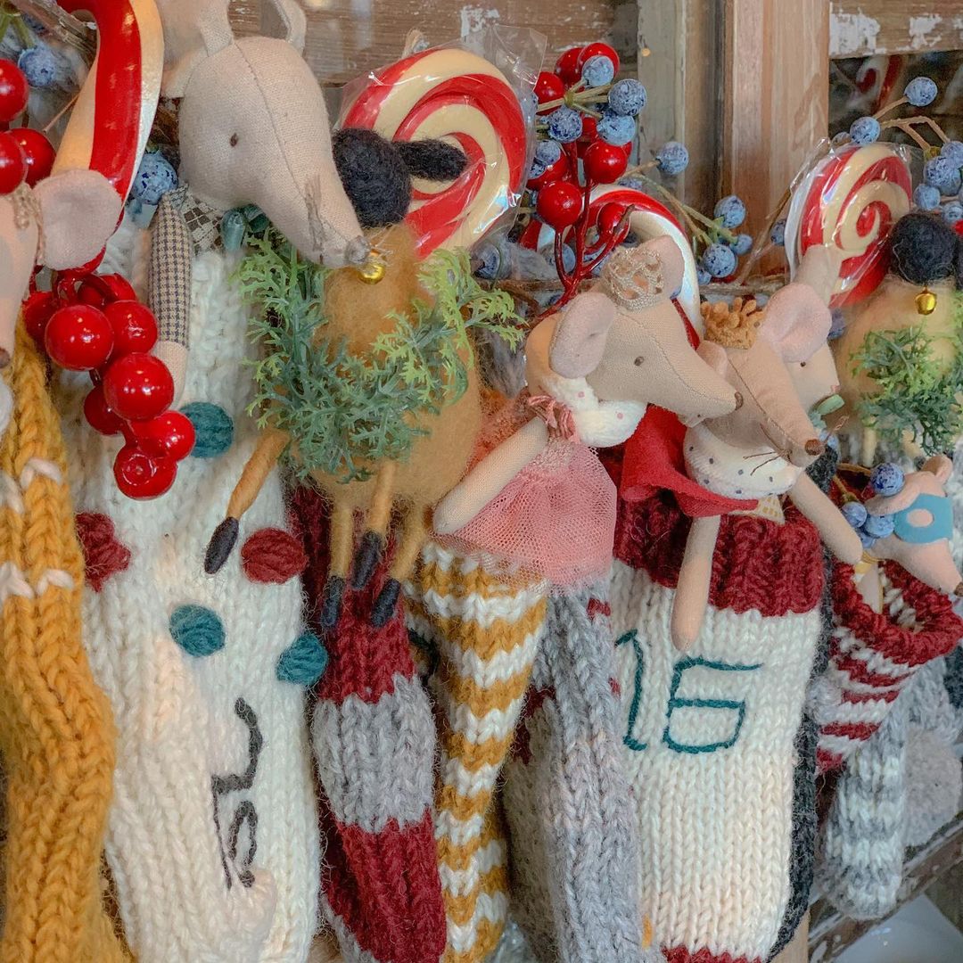 A wall decorated with multiple handcrafted Christmas stockings, hats, mittens, dolls, and various festive decorations.