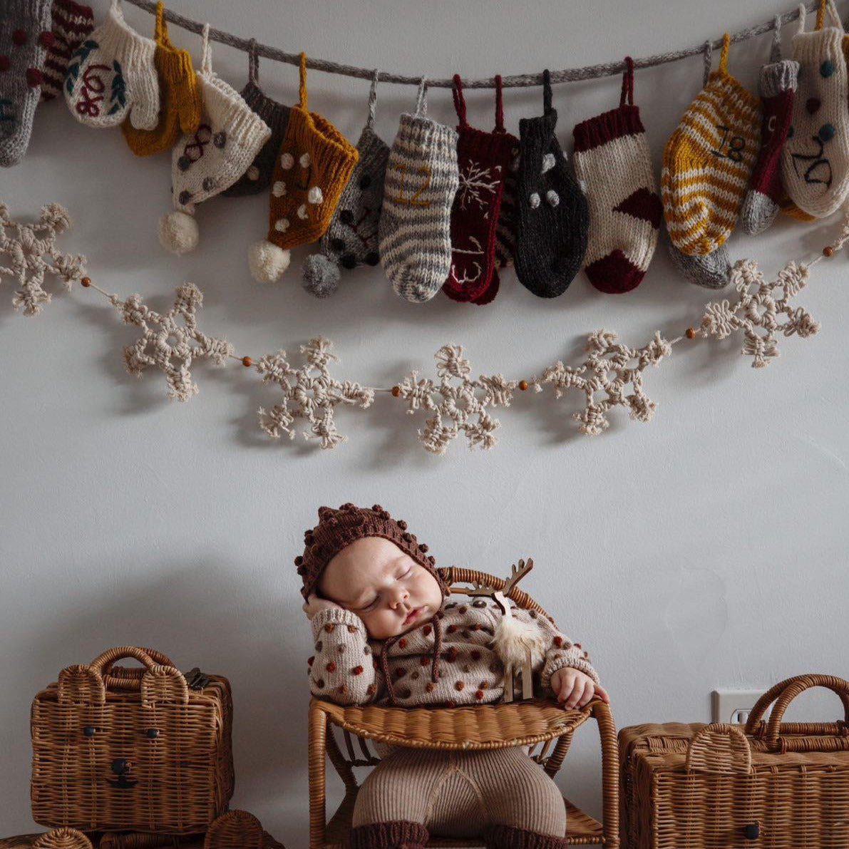 A wall decorated with multiple handcrafted Christmas stockings, hats, and mittens.