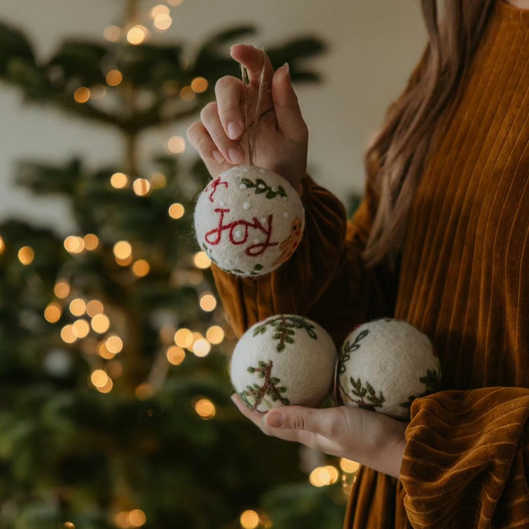 Several Bauble Joy Ornaments being held in hands, showcasing their detailed embroidery and festive design.