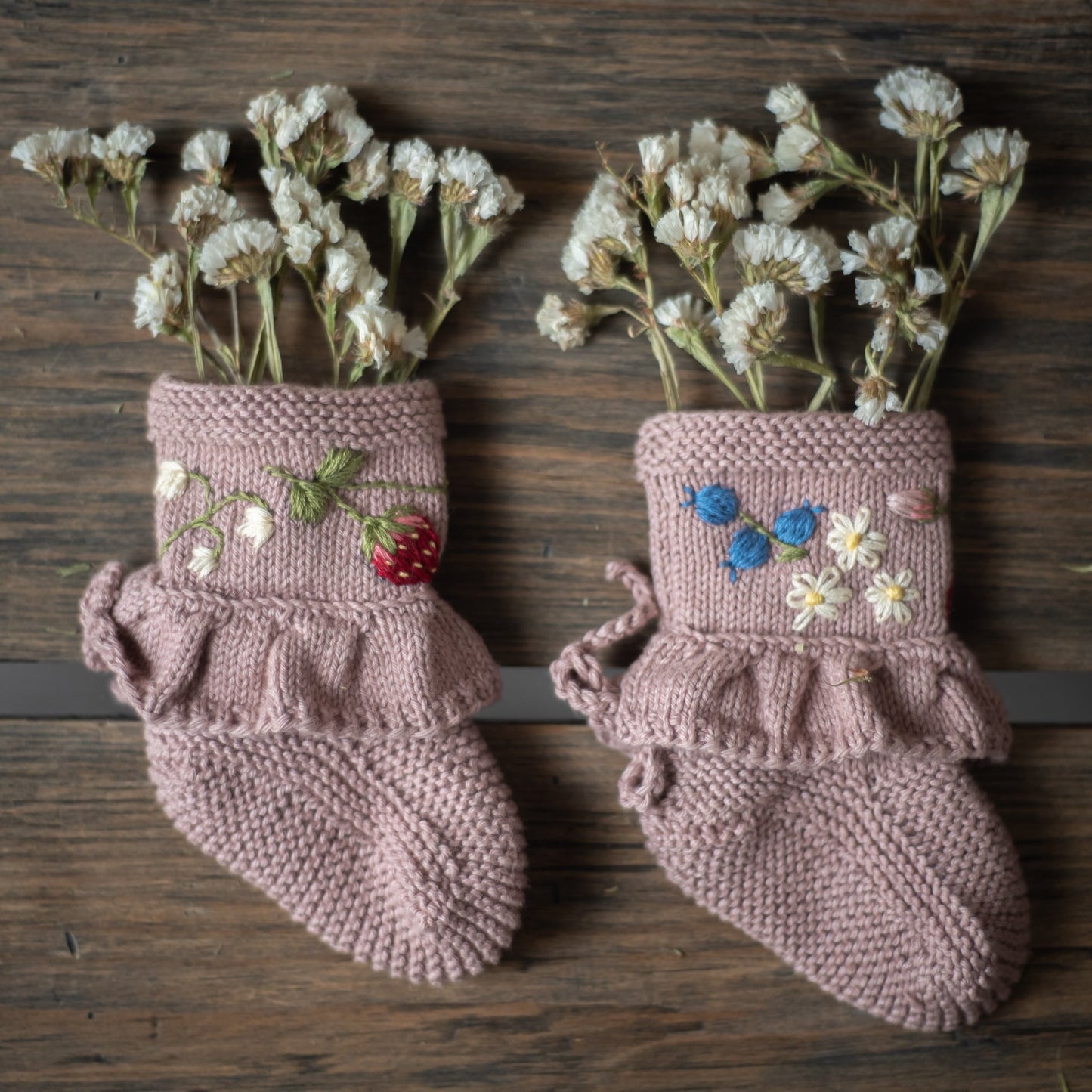 Pink knitted booties filled with white flowers as a decorative display.