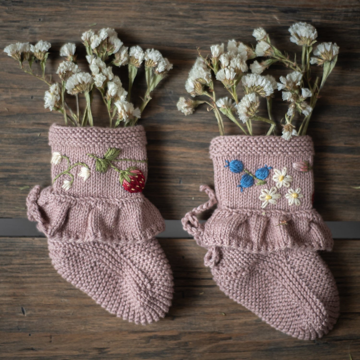 Pink knitted booties filled with white flowers as a decorative display.