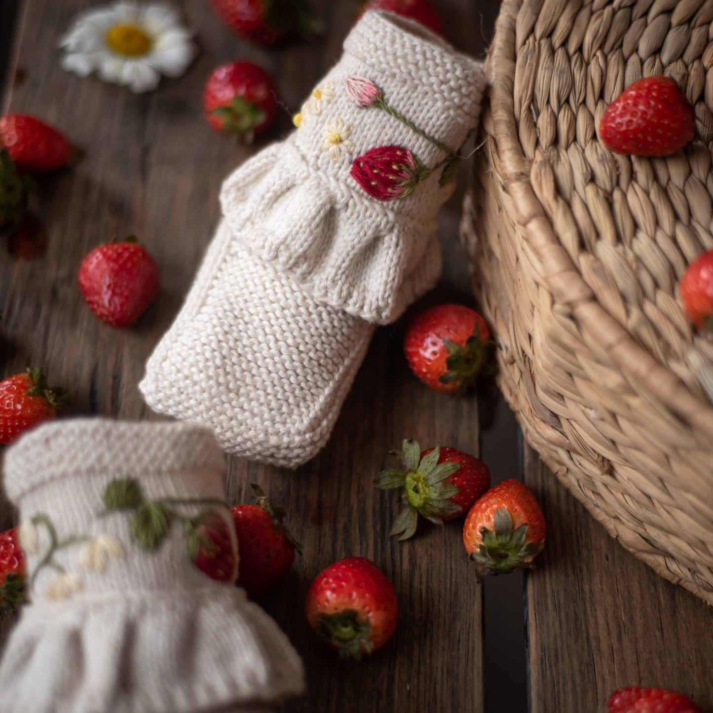 A side view of the embroidered booties among fresh strawberries, showcasing their soft texture and intricate detailing.