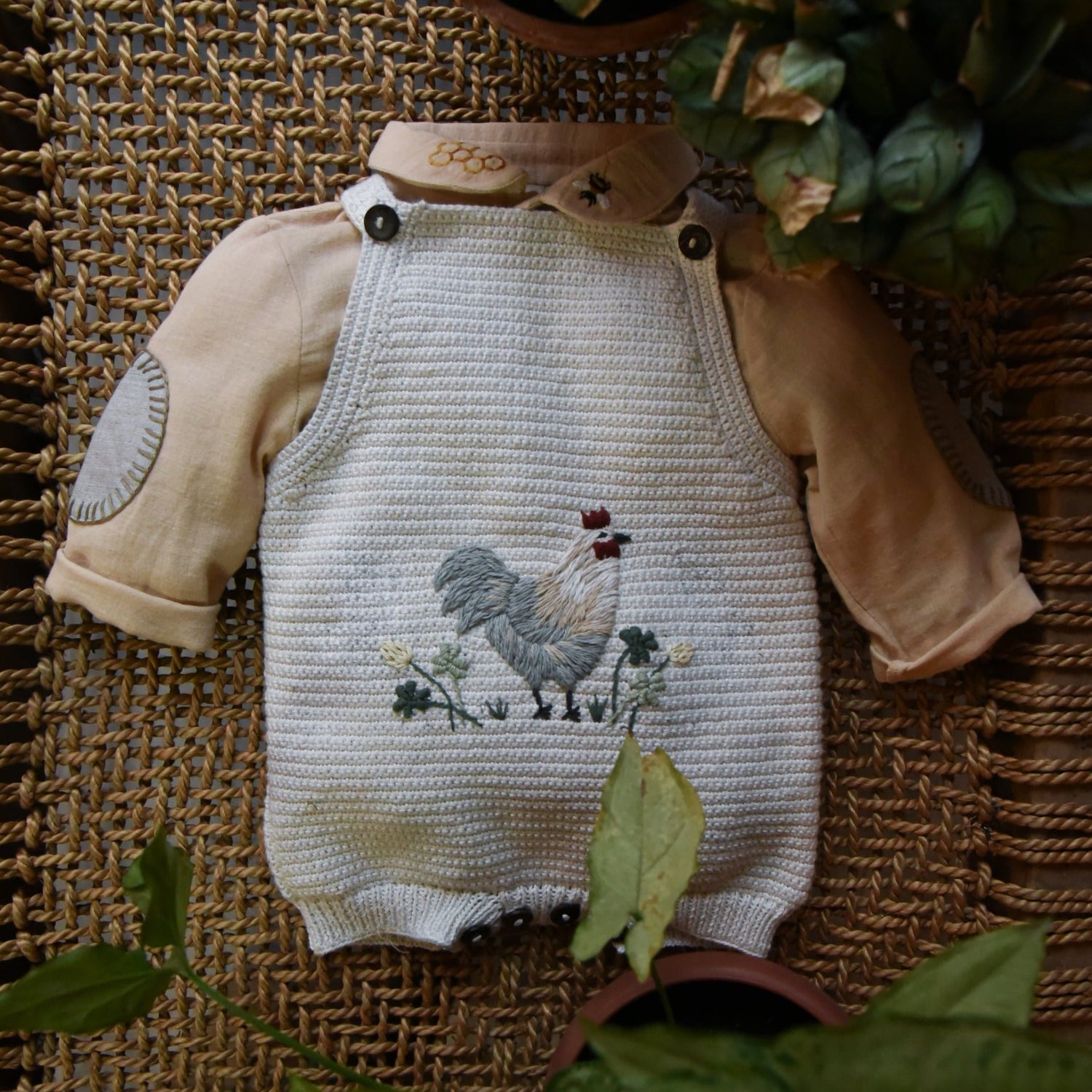 Little Farm Romper - Malt, with greenery and flowers visible in the background.