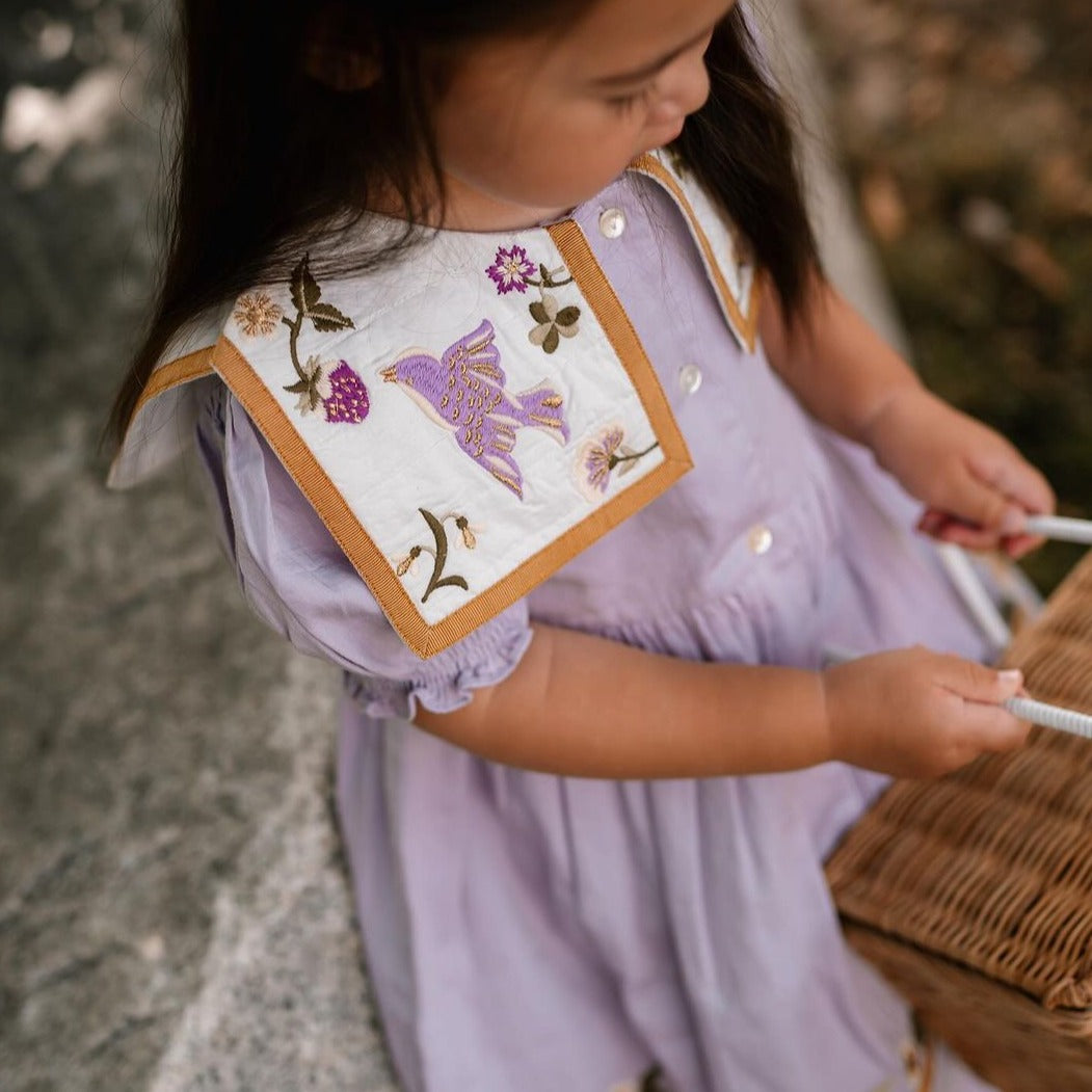Girl wearing the Birdie Bliss dress while walking gracefully through the garden.