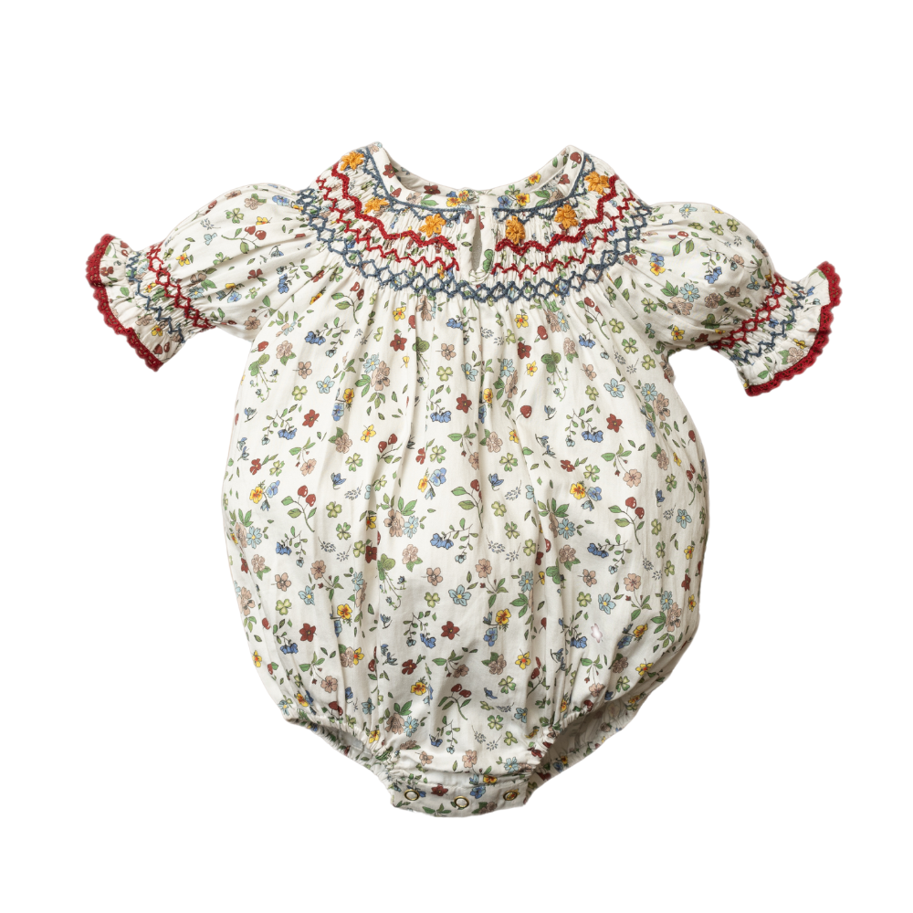 White baby romper with colorful floral print and red embroidered smock neckline
