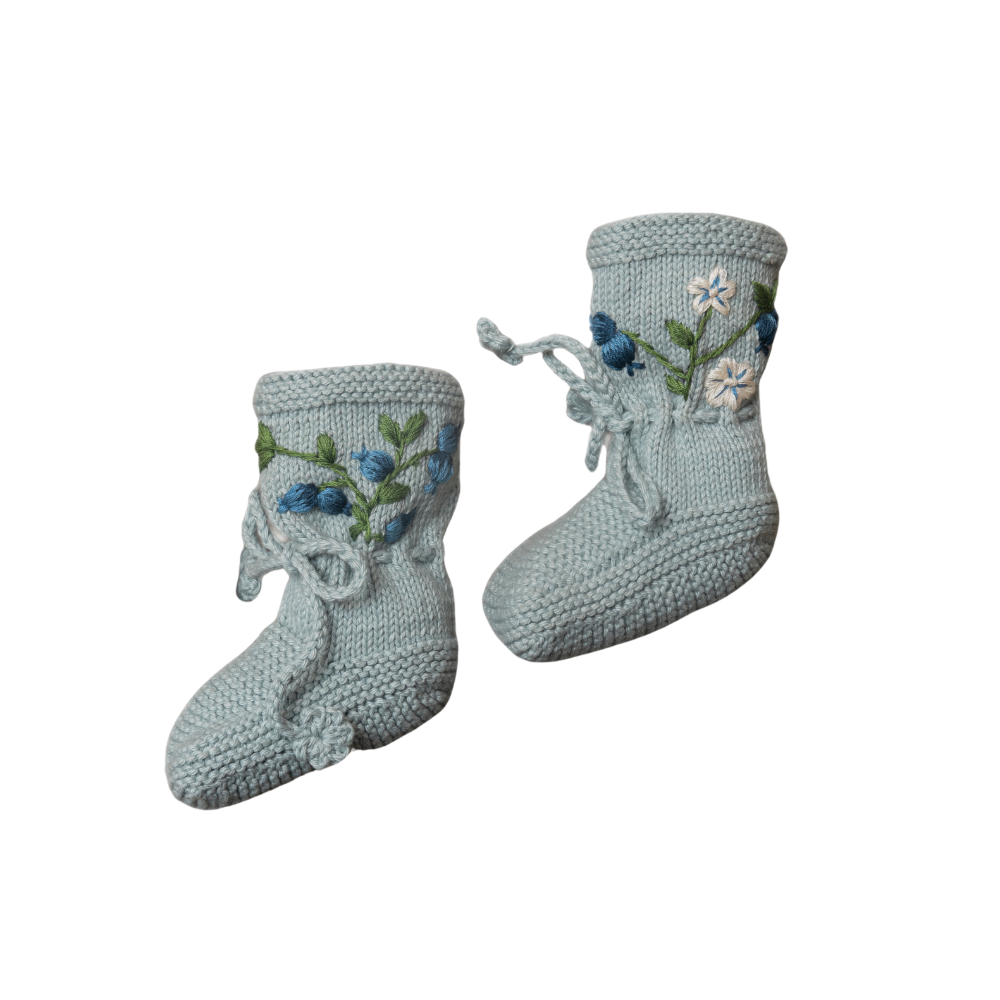 Hand-knitted duck blue cotton booties adorned with delicate blueberry embroidery and tied with soft laces.
