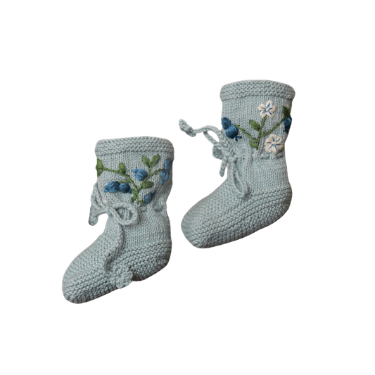 Hand-knitted duck blue cotton booties adorned with delicate blueberry embroidery and tied with soft laces.