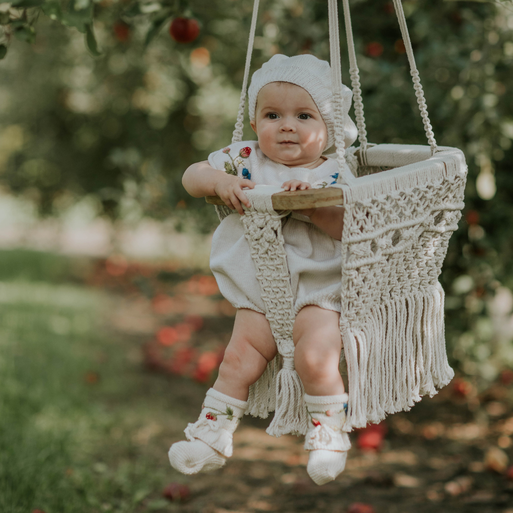 The sweetest knitted booties featuring tiny hand-stitched strawberries and flowers, paired with a charming matching romper.

