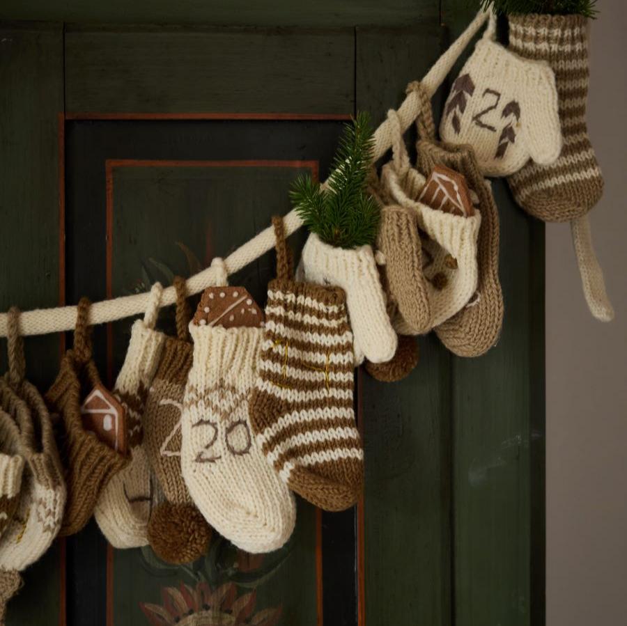 Close-up of a section of the cream wool Advent Calendar, highlighting the details of the handcrafted mittens, hats, and socks with embroidered numbers.