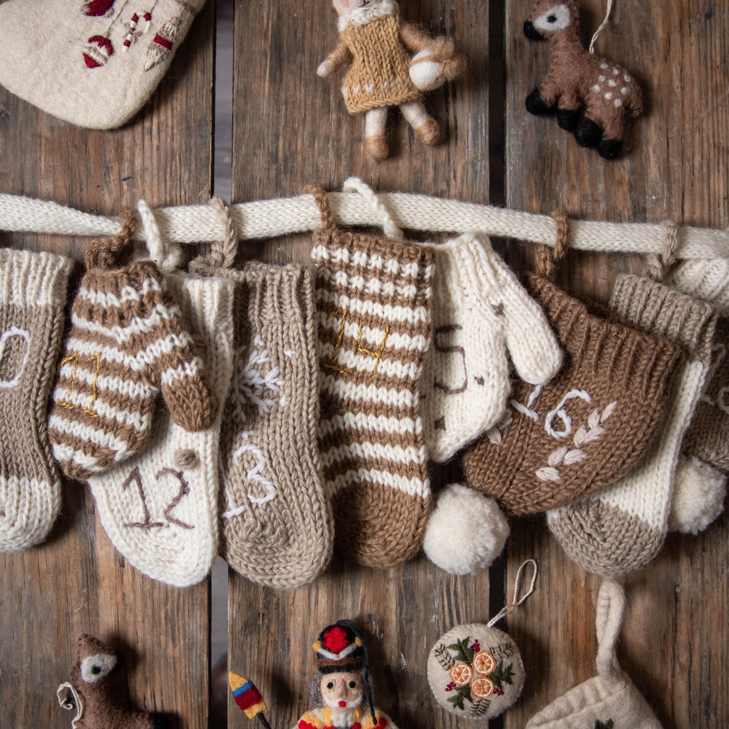 Section of the cream wool Advent Calendar on a table, surrounded by Christmas decorations and ornaments.