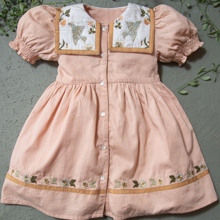 Birdie Bliss dress surrounded by greenery.







