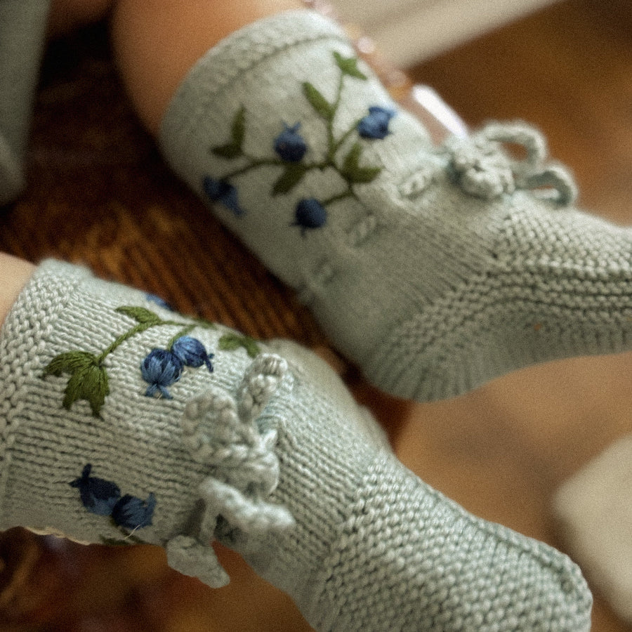 Detail view of the blueberry motifs and fine stitching on the cozy cotton booties.
