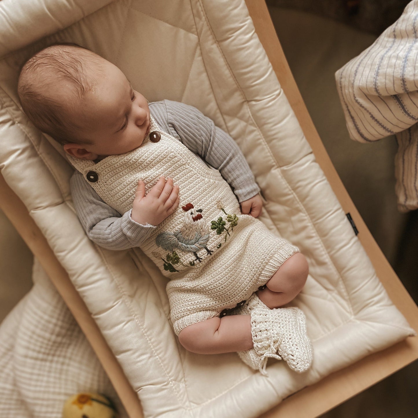 Baby wearing the Chicken Romper - Marshmellow, featuring chicken embroidery and made from organic cotton.

