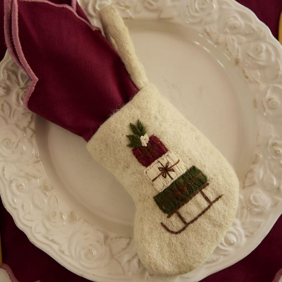 Mini Stocking Sleigh on a decorative plate, with a small gift or treat placed inside, highlighting its festive embroidery and charming design.