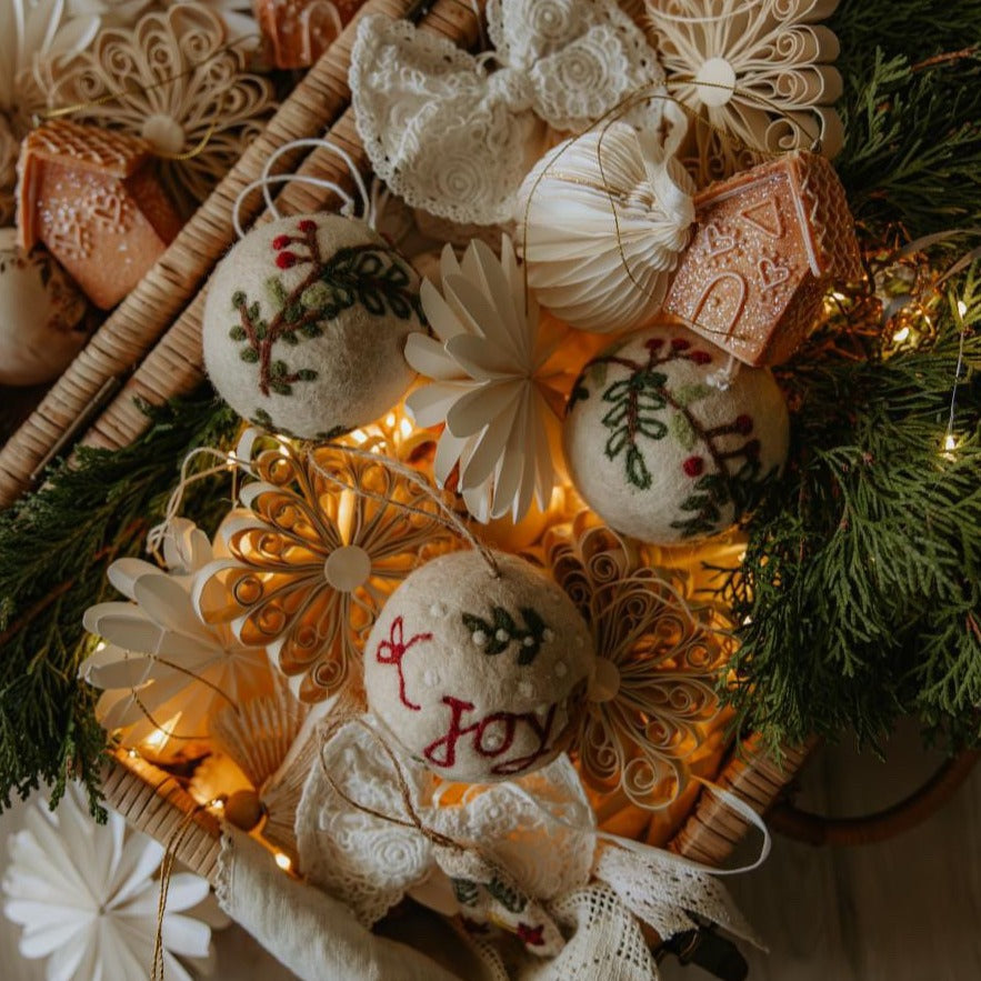 Multiple bauble ornaments with embroidered wreath designs along with other decorations