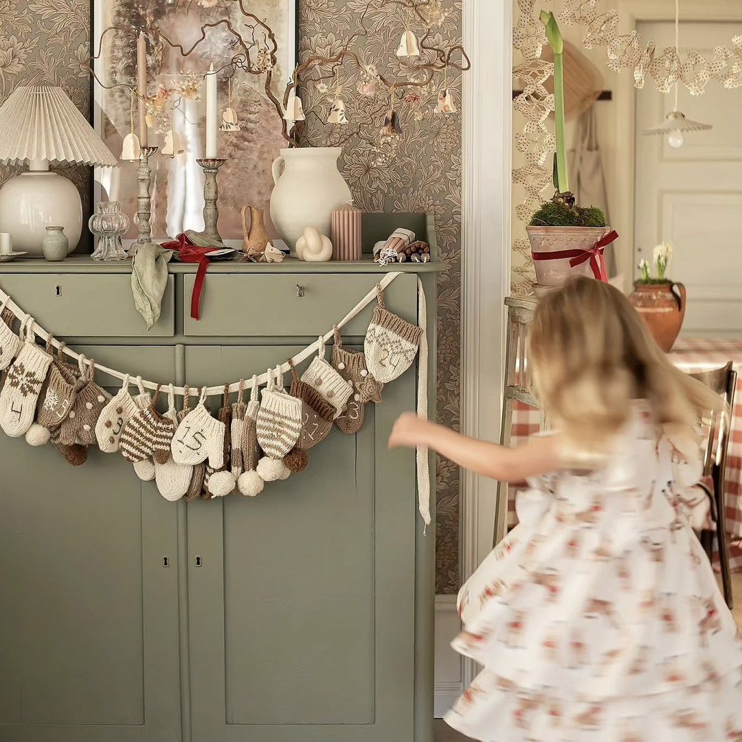 Cream wool Advent Calendar hanging on a sideboard in a room decorated with additional Christmas ornaments.