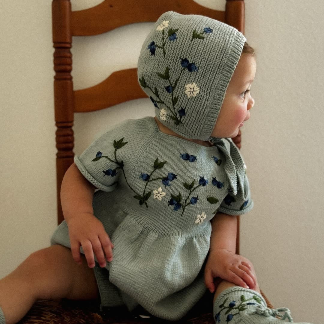 baby in knitted and embroidered blueberries romper and bonnet