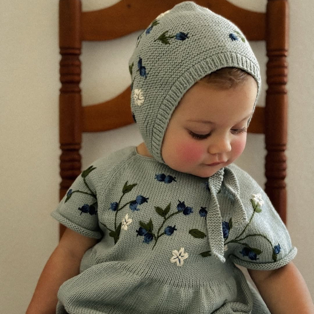 baby in knitted and embroidered blueberries romper and bonnet