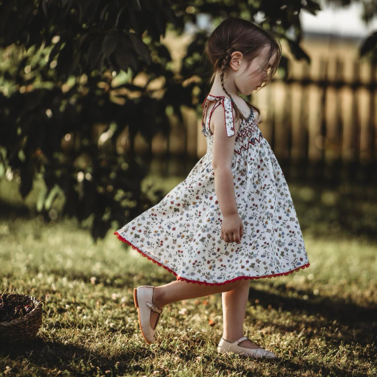 Young girl in a floral dress walking on grass with a blurred background